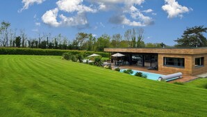 A modern house with a swimming pool, surrounded by a well-maintained lawn and trees. - Villa Cosy, Pool, Spa, Relaxation Area (Sauna & Hammam) 8 km from the beaches! (Pordic)