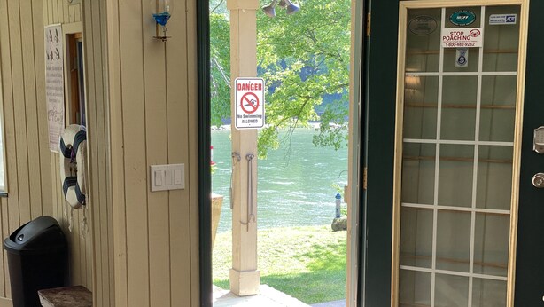 Una puerta con un cartel que dice 'No se permite nadar', un buzón y vistas a un lago.