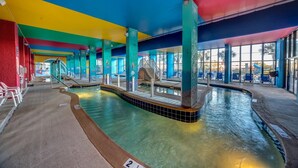 Piscina interna com água cristalina, prancha de mergulho e teto colorido.