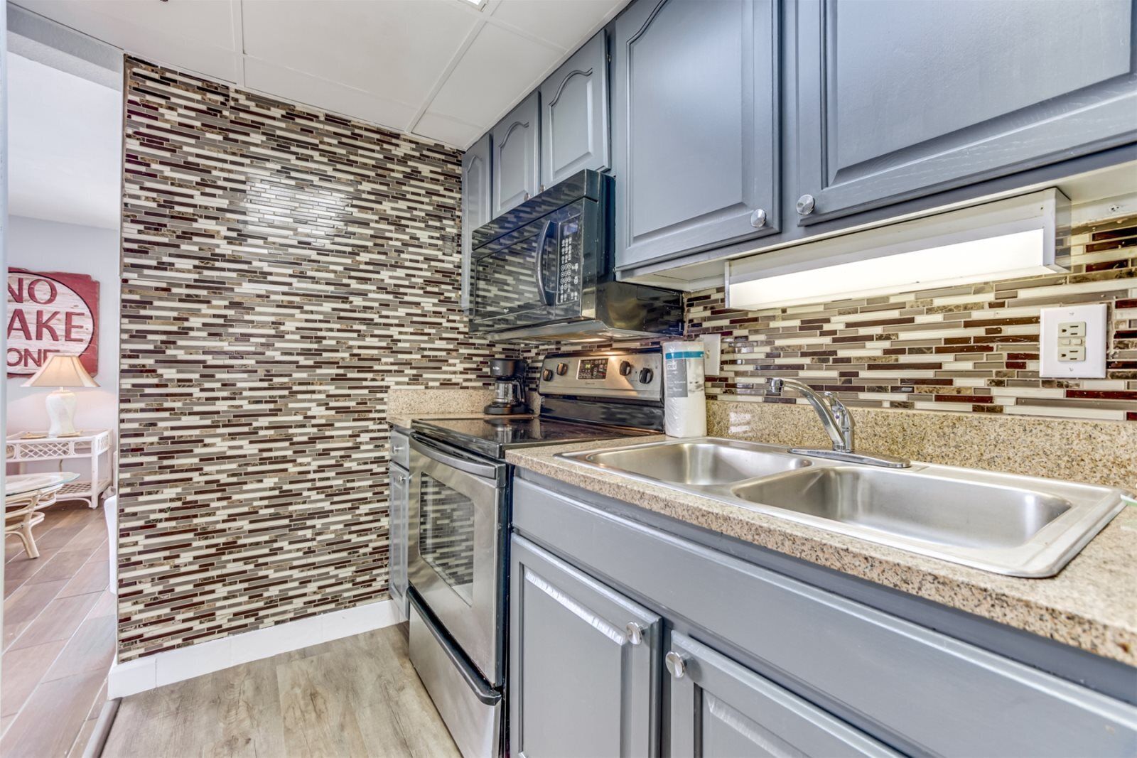 A modern kitchen with stainless steel appliances, a granite countertop, and a backsplash with a mosaic tile pattern.