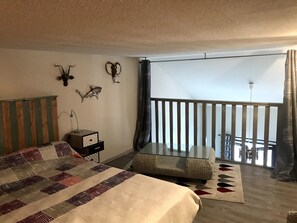 Relax in this serene bedroom with a large bed, bedside table, and balcony offering a view of the outside.