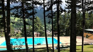 A swimming pool surrounded by trees, with a view of a town and mountains in the background. - Appartement Mezzanine Avec Vue Exceptionnelle (Barcelonnette)