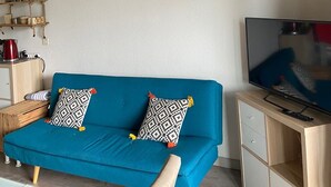A living room with a blue sofa, a mounted deer picture, a TV, and a wooden coffee table. - Appartement Mezzanine Avec Vue Exceptionnelle (Barcelonnette)