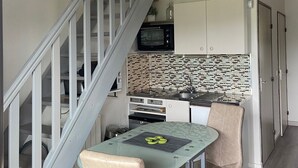 A compact kitchen with a microwave, oven, and modern backsplash. A dining table with chairs is positioned in front of the kitchen. - Appartement Mezzanine Avec Vue Exceptionnelle (Barcelonnette)