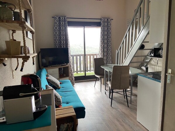 A compact living space with a sofa, a TV, a small dining table, and a kitchen area. - Appartement Mezzanine Avec Vue Exceptionnelle (Barcelonnette)