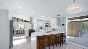 Una cocina moderna con una isla grande, taburetes de bar y vistas al exterior.