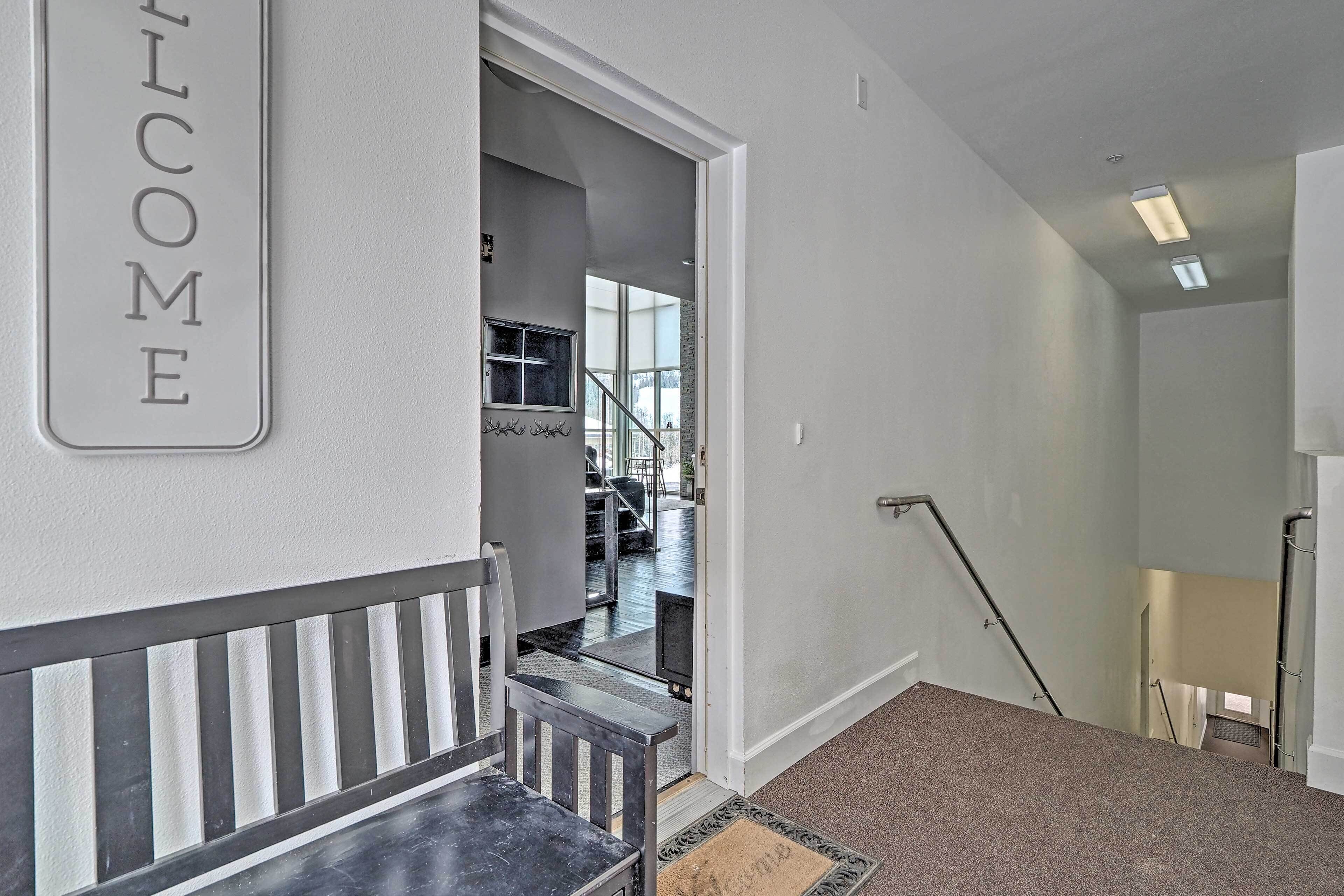 A staircase with a "WELCOME" sign, a doormat, and a view into a dining area.