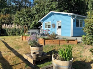 Una casa blu con un patio, circondata da una recinzione di legno e diverse piante.