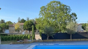 En swimmingpool med ett trädäck runt om, omgiven av ett staket och träd.