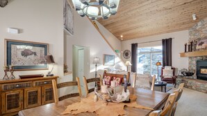 A dining area with a wooden table, leather table runner, and a stone fireplace.