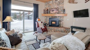 A cozy living room with a stone fireplace, leather sofas, and a television.