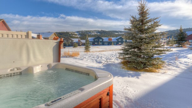 A hot tub in a snowy outdoor setting with a clear sky.