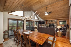 A spacious living area with a wooden dining table, chairs, a sofa, and a fireplace.
