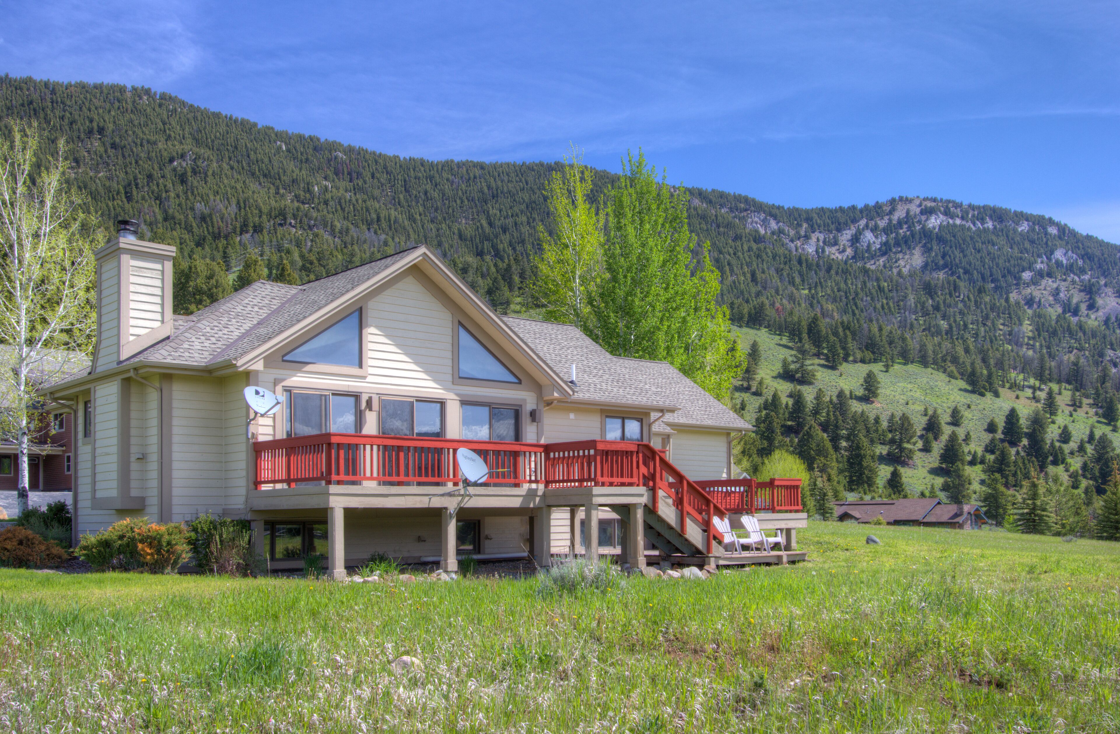 A two-story house with a balcony, a satellite dish, and a view of a forested mountain.