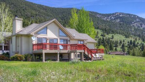 A two-story house with a balcony, a satellite dish, and a view of a forested mountain. - Private Hot Tub | Golf Course | Nordic Skiing | Big Sky Awaits (Big Sky)