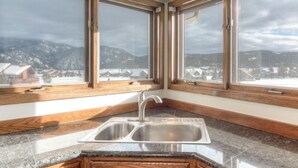 A kitchen with a double sink, wooden countertops, and large windows offering a view of a snowy landscape. - Private Hot Tub | Golf Course | Nordic Skiing | Big Sky Awaits (Big Sky)