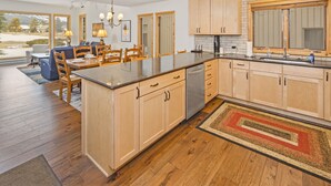 Une cuisine moderne avec des meubles en bois, un îlot central et une grande fenêtre donnant sur un paysage enneigé.