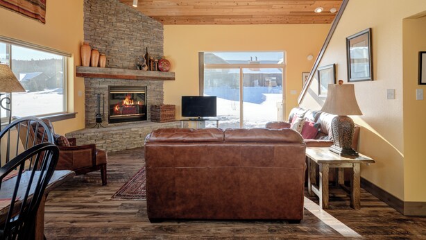 Ein gemütliches Wohnzimmer mit Kamin aus Stein, einer Ledersofa und einem Fernseher.