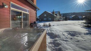 Ein Holzhaus mit Whirlpool im Schnee.
