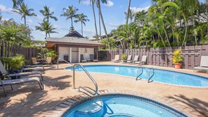 Une piscine avec des chaises longues et un petit bâtiment en arrière-plan.