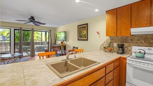Une cuisine équipée d’un évier, d’une cuisinière et d’un coin repas avec des chaises et une table.