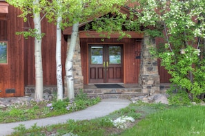 A rustic wooden house with a stone entrance and a wooden door.