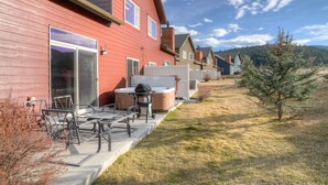Une maison rouge dotée d’un patio, d’un espace salon extérieur et d’un jacuzzi.