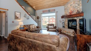 A cozy living room with a stone fireplace, leather sofas, and a wooden ceiling. - Beautiful home w/gorgeous views & fireplace, close to Big Sky Town Center - Firelight Cottage (Big Sky)