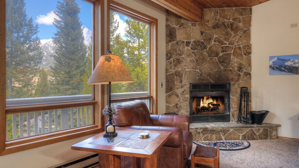 A cozy room with a stone fireplace, leather sofa, and a table with a lamp. - Home in Big Sky Town Center w/fireplace & community pool/hot tub - Hidden Gem in the Trees (Big Sky)