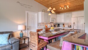 Una cocina moderna con armarios blancos, una isla central y lámparas colgantes.