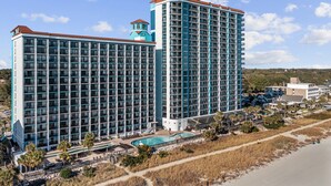 Ein Hochhotel mit mehreren Stockwerken, einem Pool und Blick auf den Strand.