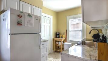 A compact kitchen with a refrigerator, a coffee maker, and a sink.