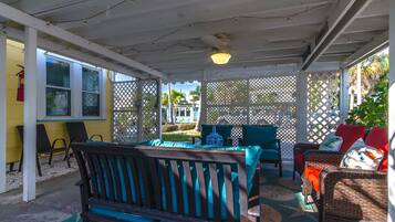 A covered outdoor seating area with a table and chairs, a wooden bench, and a lattice fence.