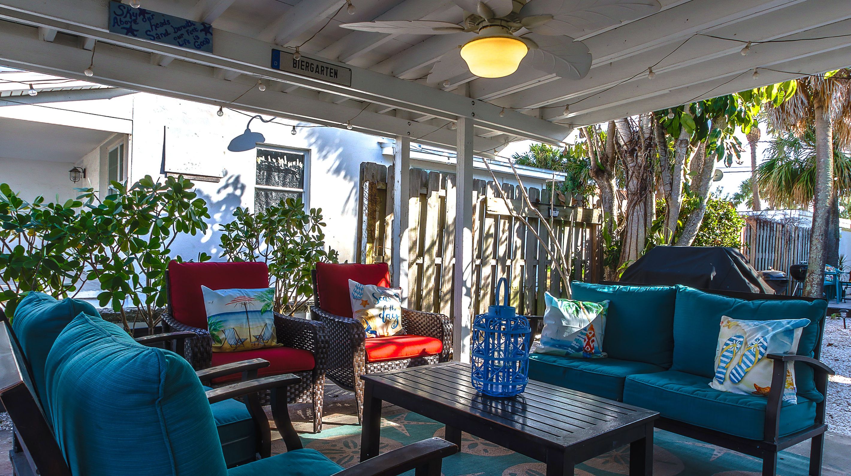 An outdoor seating area with wicker furniture, a wooden table, and a ceiling fan.