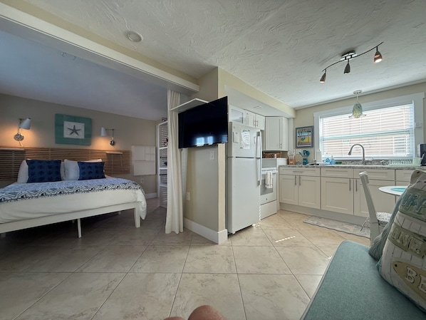 Un espacio habitable pequeño con cama, kitchenette y zona de comedor.