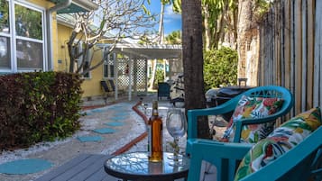 Eine Terrasse mit Gartenmöbeln, einem Tisch mit Flasche und Glas sowie einem überdachten Sitzbereich.