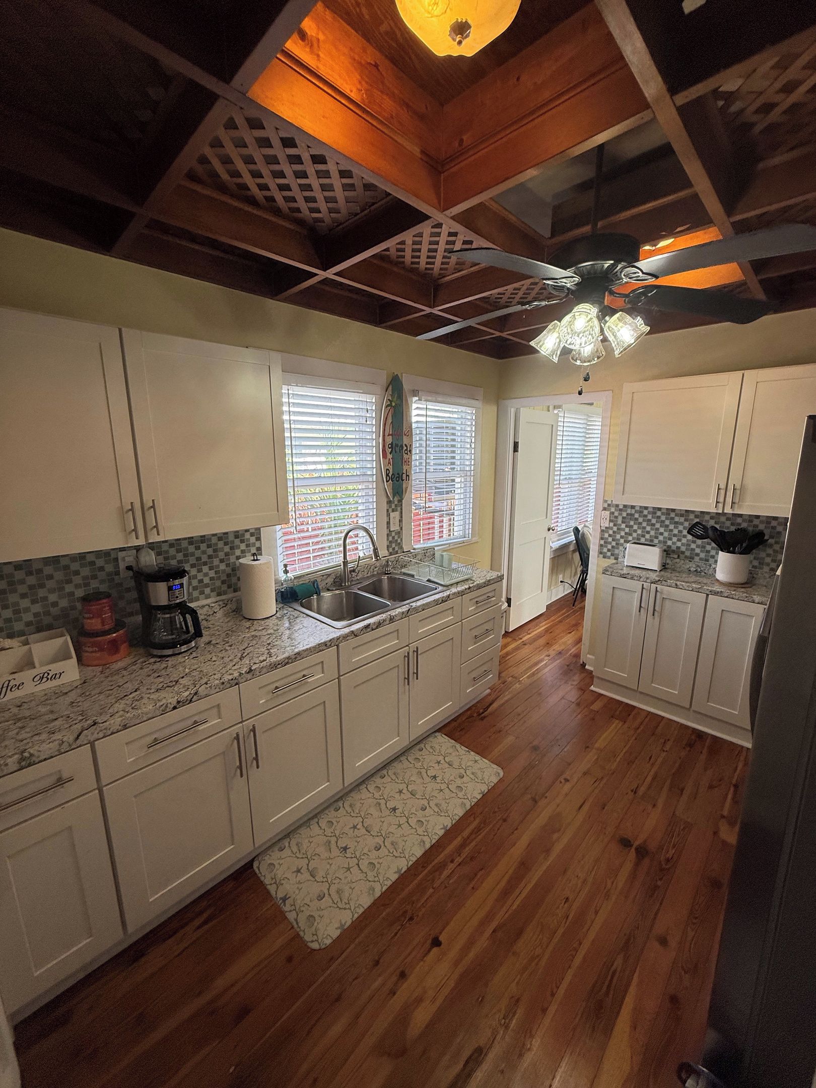 A kitchen with white cabinets, a granite countertop, and a wooden ceiling.