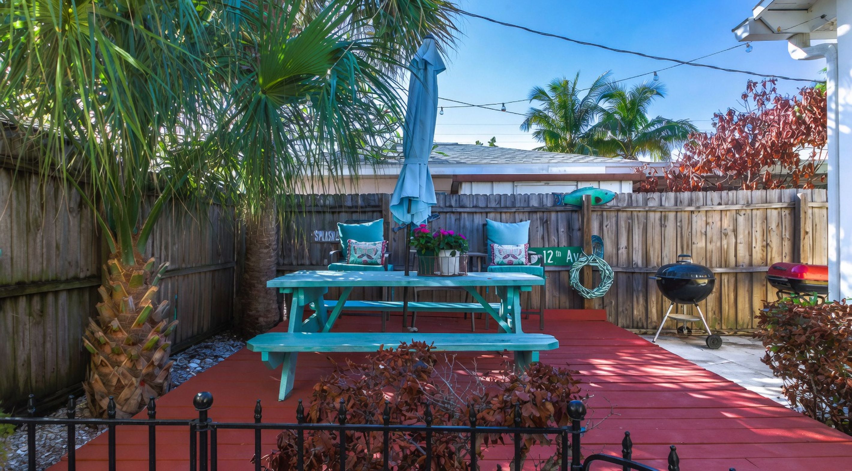 A backyard with a picnic table, a barbecue grill, and a wooden fence.