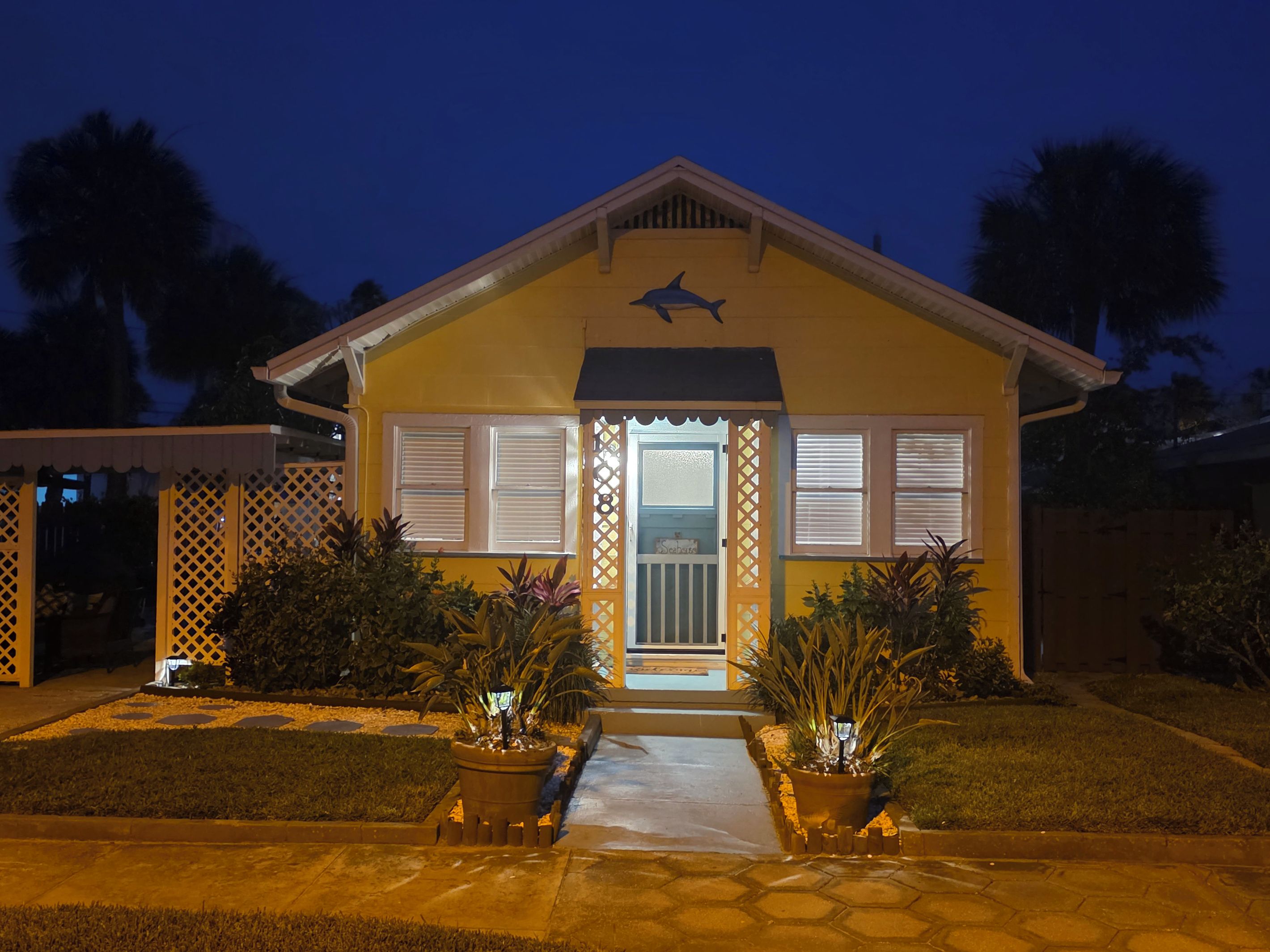 A house with a front porch, a small garden, and a decorative dolphin symbol above the entrance.