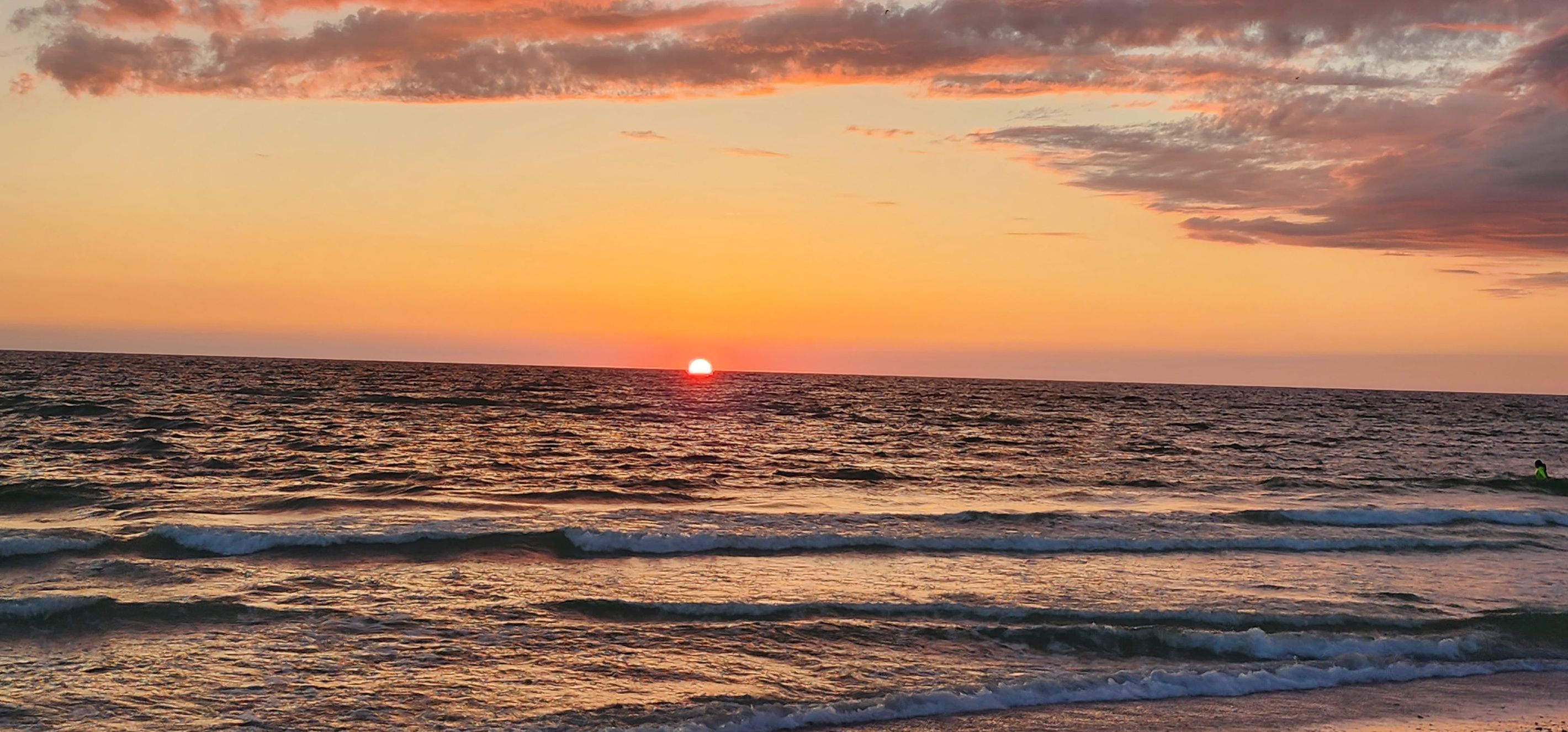 A sunset over the ocean with waves.