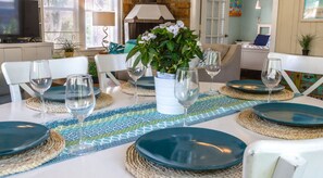 A dining table set with blue plates, wine glasses, and a centerpiece of white flowers.