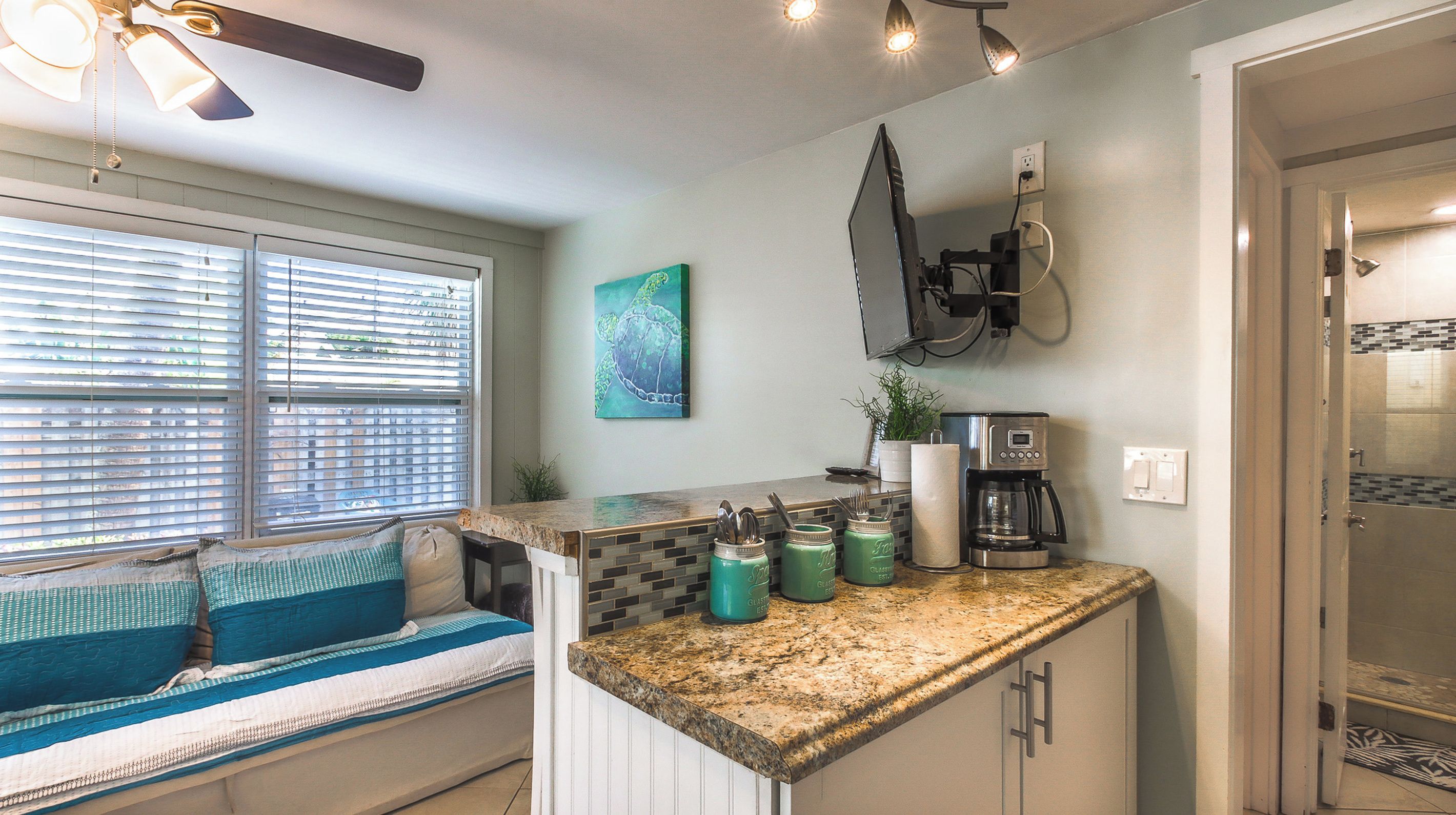 A kitchen with a built-in seating area, a coffee maker, and a wall-mounted television.