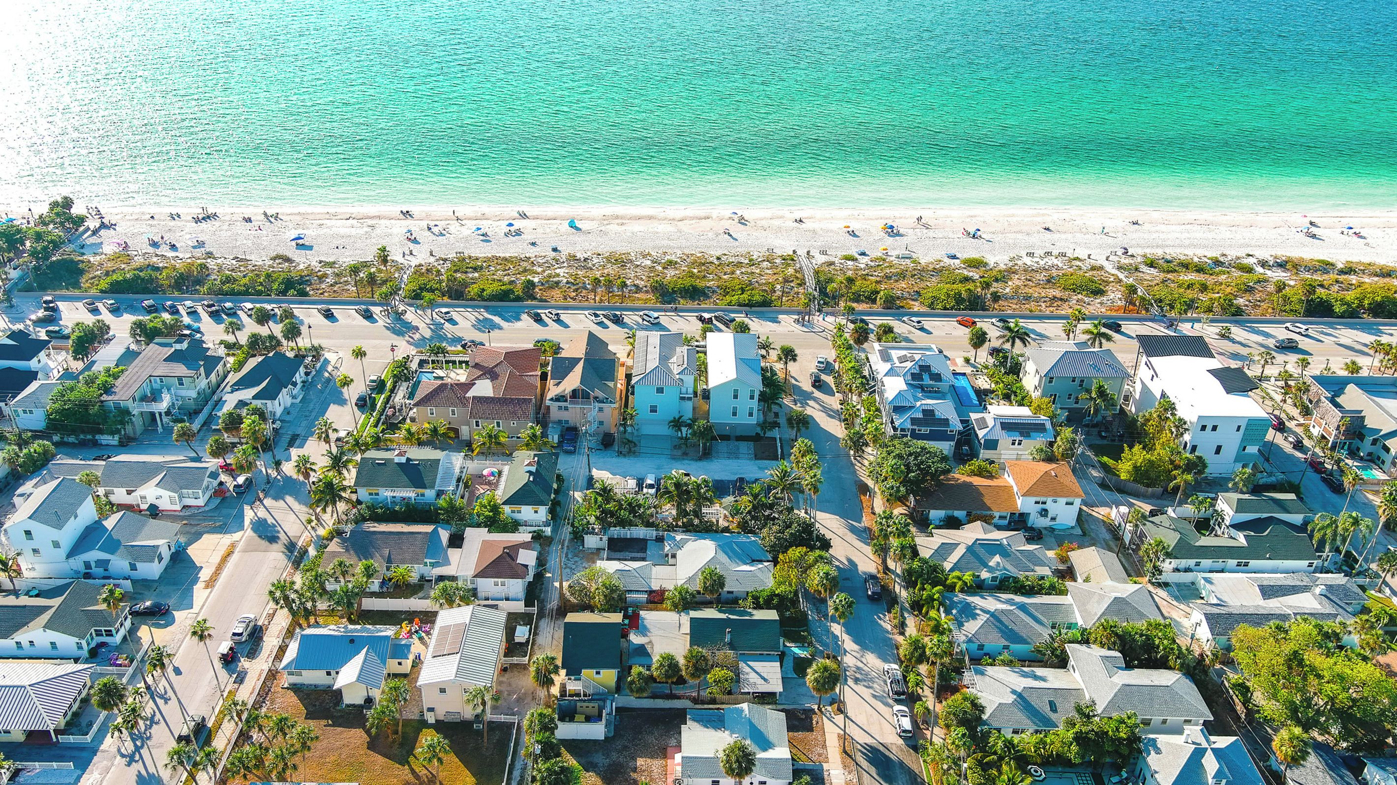 A coastal residential area with houses, a beach, and a road.