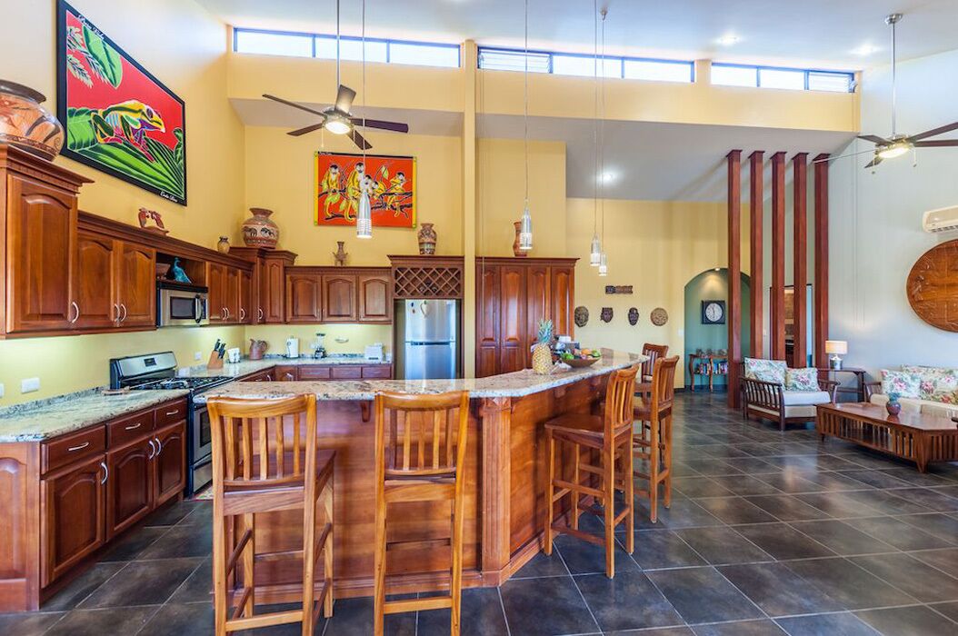 Un'ampia cucina con una grande isola, mobili in legno e un'area pranzo con sedie.
