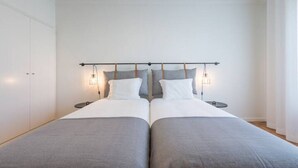Ein Doppelbett mit Kopfteil, Nachttischen und Wandleuchten.