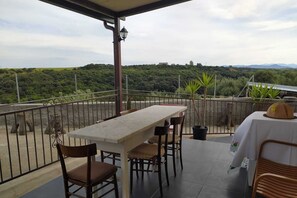 Enjoy al fresco dining on the terrace with a table set amidst lush green surroundings.