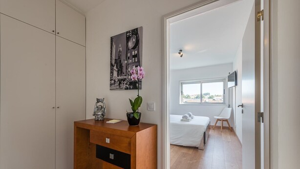 A bedroom with a bed, a window, and a view of the cityscape.