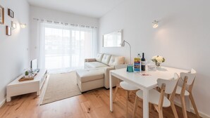 Een moderne, goed verlichte woonkamer met een bank, een eettafel en een televisie.