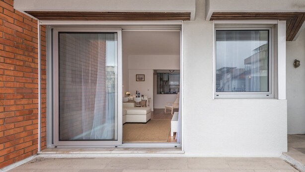 Een modern appartement met een schuifdeur die uitkomt op een woonruimte, keuken en balkon.