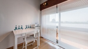 A modern room with a white desk, a chair, a ladder, and a large window with blinds. - GuestReady - Urban escape with a view (Porto)